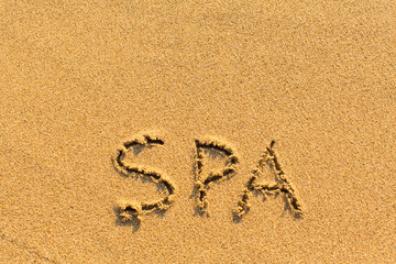 Spa - inscription by hand on a sandy golden sea beach.