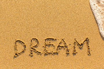 Dream - drawn by hand on a sandy golden sea beach.