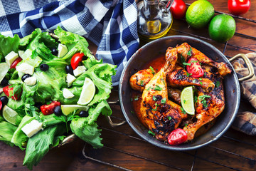 Grilled chicken legs, lettuce and cherry tomatoes limet olives. Traditional cuisine. Mediterranean cuisine.