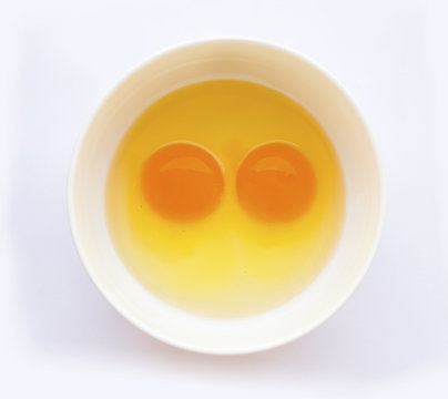 Egg yoks un-cooked in white bowl, solid white background