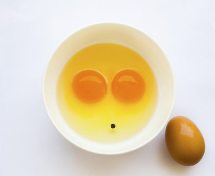 Egg yoks un-cooked in white bowl, solid white background