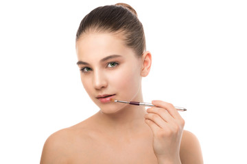 Fototapeta premium Portrait of beautiful young brunette woman with clean face. Beauty spa model girl with perfect fresh clean skin applying cosmetic brush. Youth and skin care concept. Isolated on a white background.