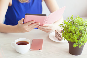 woman with pink phone reading the e-book in a cafe