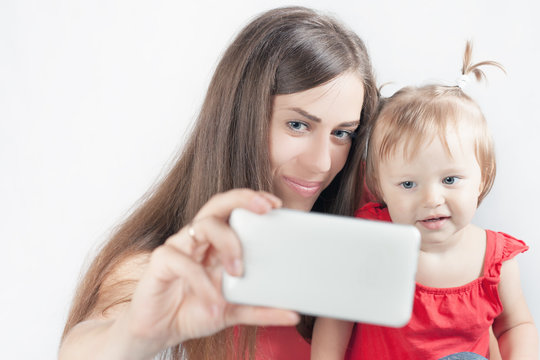 Funny baby and mother make selfie on mobile phone