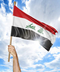 Person's hand holding the Iraqi national flag and waving it in the sky, 3D rendering