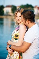 Obraz premium Pretty young couple lovely hugging and looking at camera at water background in sunny day, Close up photo with copyspace