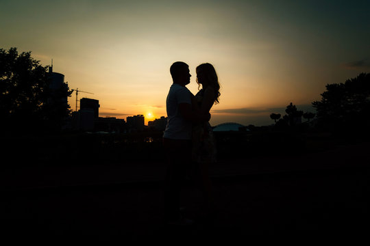 Silhouettes of romantic couple kissing in the city with copyspace