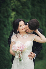 Beautiful romantic wedding couple of newlyweds hugging in park on sunset