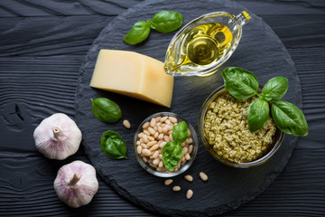 Above view of a stone slate with basil pesto and its ingredients