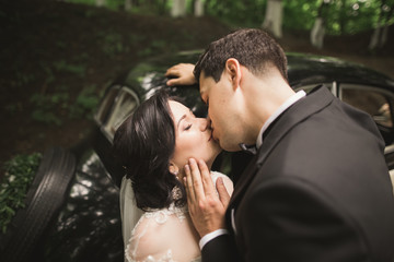 Beautiful wedding couple posing near splendid retro car