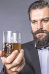 Portrait of a bearded young man with retro look holding a glass