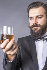 Portrait of a bearded young man with retro look holding a glass