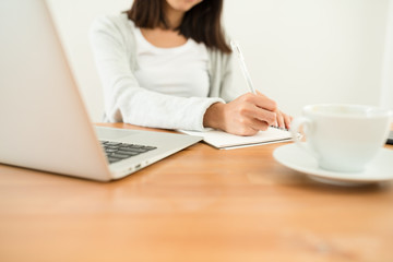 Woman writing on the note book on her desk