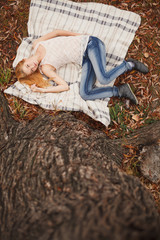 redhead girl lying on leaves in city park, fall season