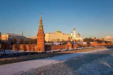 Red walls of sunset Kremlin in Moscow near iced river in winter