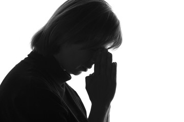isolated black and white portrait of a woman with her hands folded near the bridge of the nose due to despair