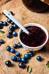 blueberries and blueberry jam in a white bowl with spoon