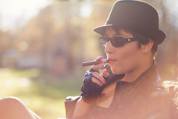 The girl in a black hat smokes a cigar