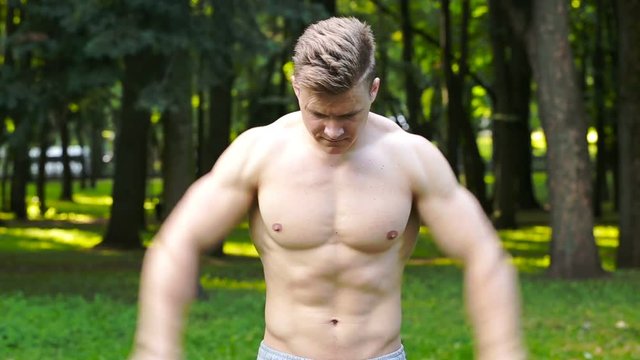man with a beautiful body, do exercises in the park