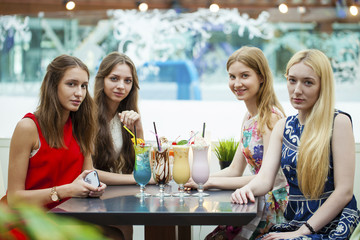 Close up four attractive young women drinking cocktails in shopp