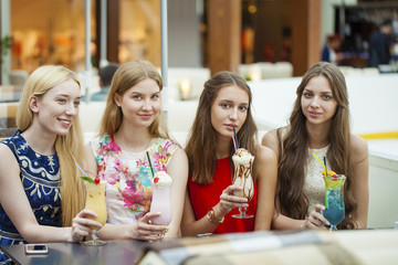 Close up four attractive young women drinking cocktails in shopp