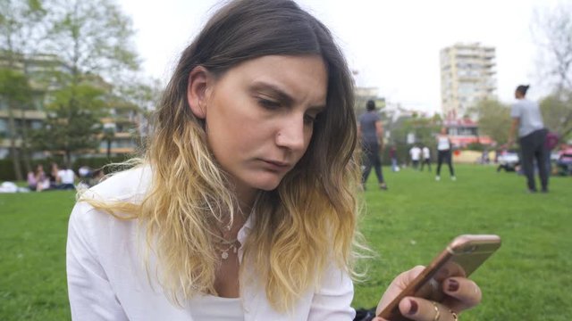 Young woman reading message on phone in park