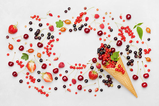 Frame with colorful berries in waffle cone on light background top view. Dietary and healthy dessert. Flat lay styling.