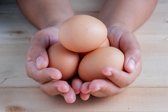 hand holding egg on wooden background