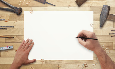 Drawing on paper. Old tools beside on wooden desk.