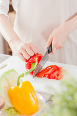 エプロンを着た女性、パプリカを切る