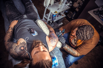 Fototapeta na wymiar Professional tattoo artist working tattooing in tattoo parlor