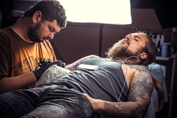 Fototapeta premium Tattoo artist works in tattoo parlour