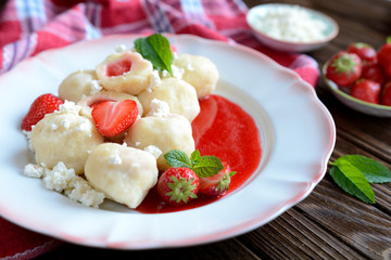 Sweet boiled dumplings filled with strawberries with a curd and a strawberry sauce
