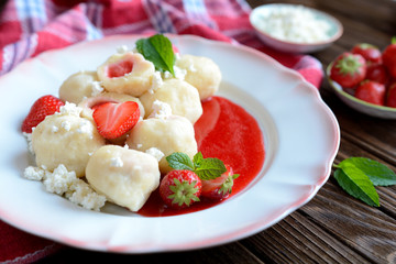 Sweet boiled dumplings filled with strawberries with a curd and a strawberry sauce
