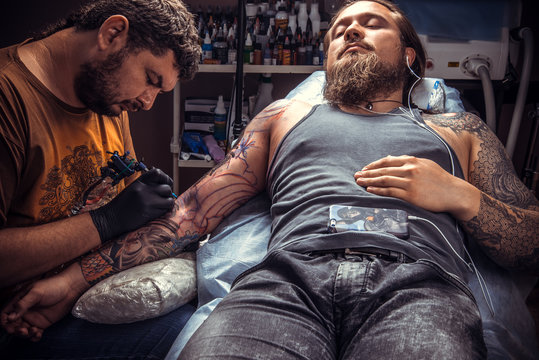 Man wearing gloves makes tattoo in tattoo parlour
