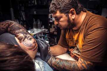 Obraz premium Professional tattoo artist making a tattoo in tatoo salon