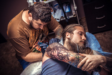 Fototapeta premium Professional tattooist at work in tattoo studio