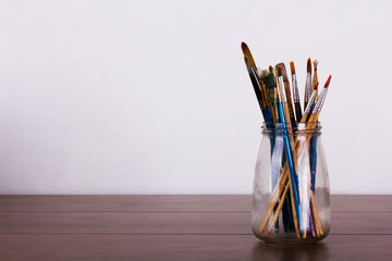 Paint brushes in a pot against a white background