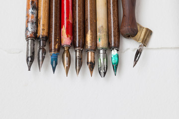 Vintage fountain pen collection. Aged colorful artist pens, textured white paper background. Artist tools concept. macro,