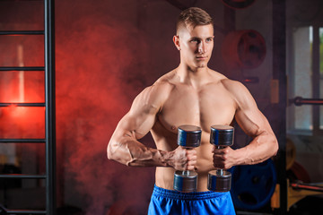 Fototapeta na wymiar Man doing heavy weight exercise with dumbbells in gym