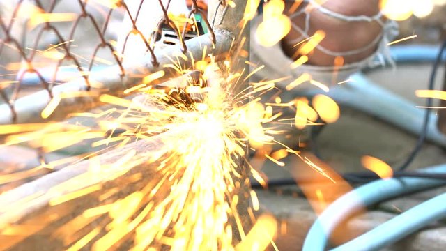 4K footage of Worker cutting metal with hand cutting machine and sparks flew fling to camera
