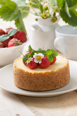Cheesecake with strawberries on a plate, a bowl of strawberries on a wooden background