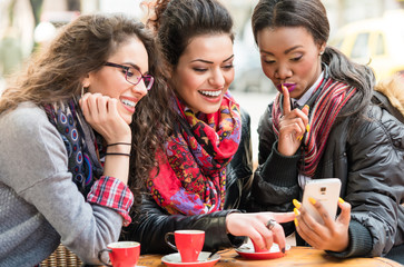 Women in cafe showing pictures on smart phone