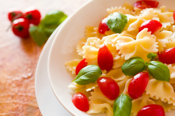 Closeup of Farfalle pasta with cherry tomatoes and basil over a