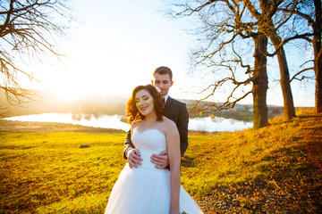 beautiful happy stylish bride with elegant groom on the background of beautiful trees in the autumn park