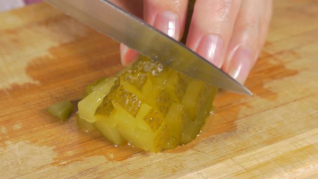 Pickled cucumber chop up smaller pieces with knife on wooden board 4K 2160p UHD panning footage - Gherkin cut up in small pieces on wooden table 4K 3840X2160 UHD viudeo 