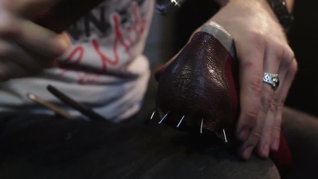 Shoemaker sews shoes. Hammering leather.