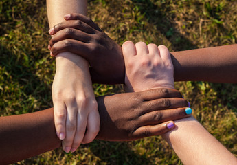 Hands of multiracial friends holding each other as team, cooperation concept