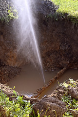 The water jet in the form of leakage in the damaged metal pipe at the production site