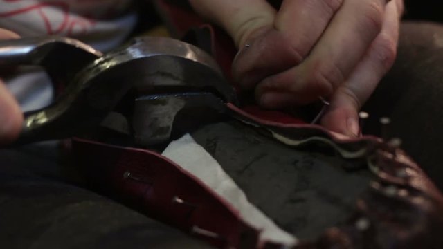 Shoemaker sews shoes. Hammering shoe leather